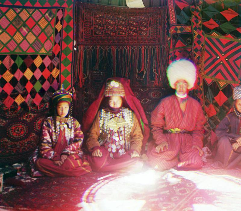 four_people_seated_on_a_carpet_in_front_of_a_backdrop_of_textiles.jpg