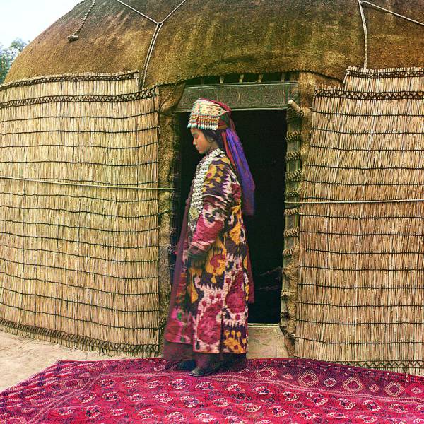 full-length_profile_portrait_of_a_woman_possibly_turkman_or_kirgiz_standing_on_a_carpet_at_the_entrance_to_a_yurt_dressed_in_traditional_clothing_and_jewelry.jpg