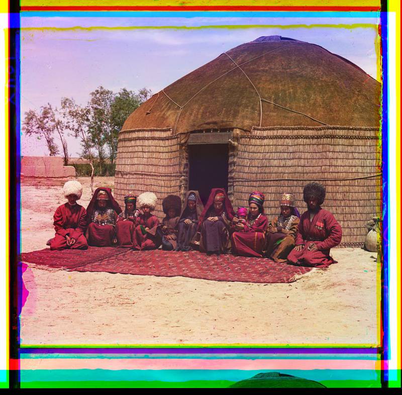 group_of_eleven_adults_and_children_seated_on_a_rug_in_front_of_a_yurt.jpg