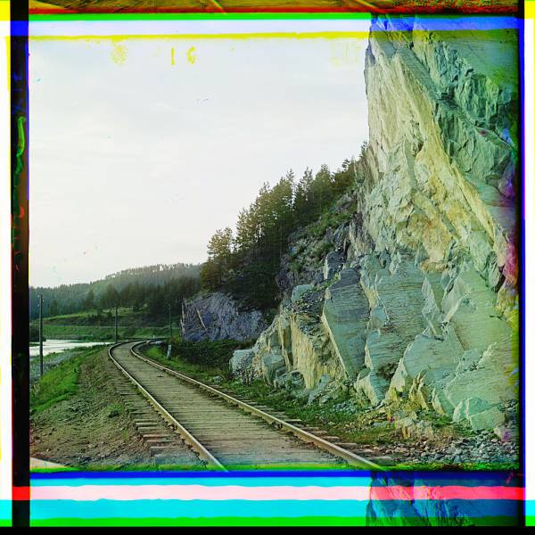 railroad_tracks_and_utility_poles_along_a_waterway_and_cliff.jpg