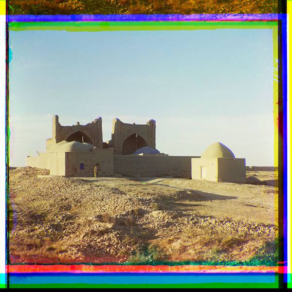 walled_adobe_structure_with_domes_and_arches_in_desert_area_with_man_posed_in_front..jpg