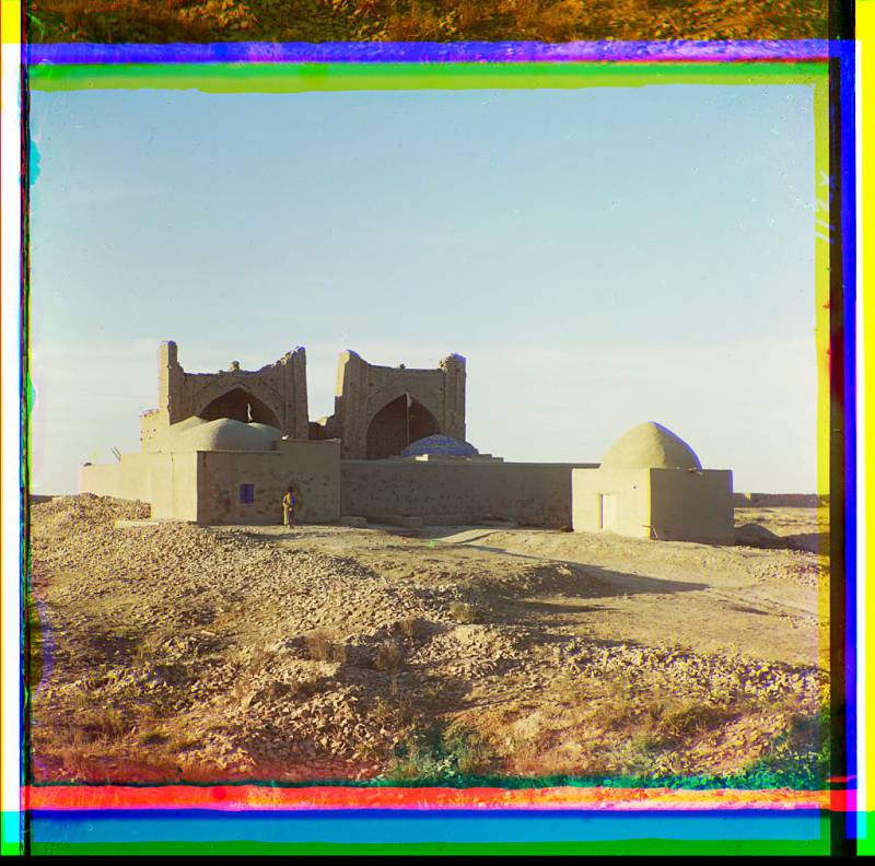 walled_adobe_structure_with_domes_and_arches_in_desert_area_with_man_posed_in_front..jpg