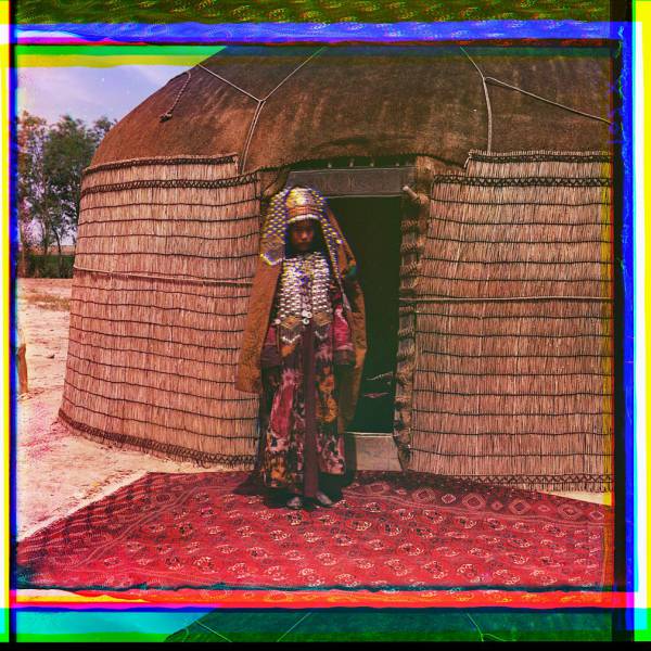 woman_in_traditional_dress_and_jewelry_standing_on_rug_in_front_of_yurt..jpg